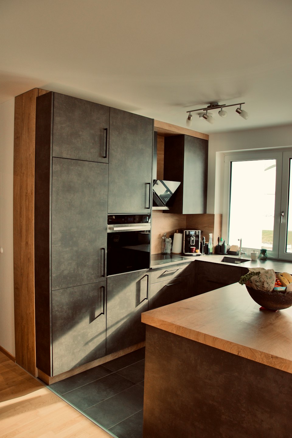 Modern kitchen with dark cabinets and a wooden island.